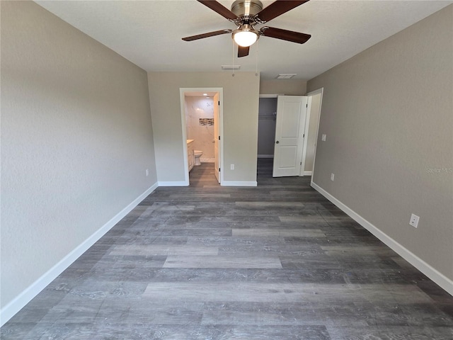 unfurnished bedroom with visible vents, ensuite bathroom, dark wood finished floors, baseboards, and a spacious closet