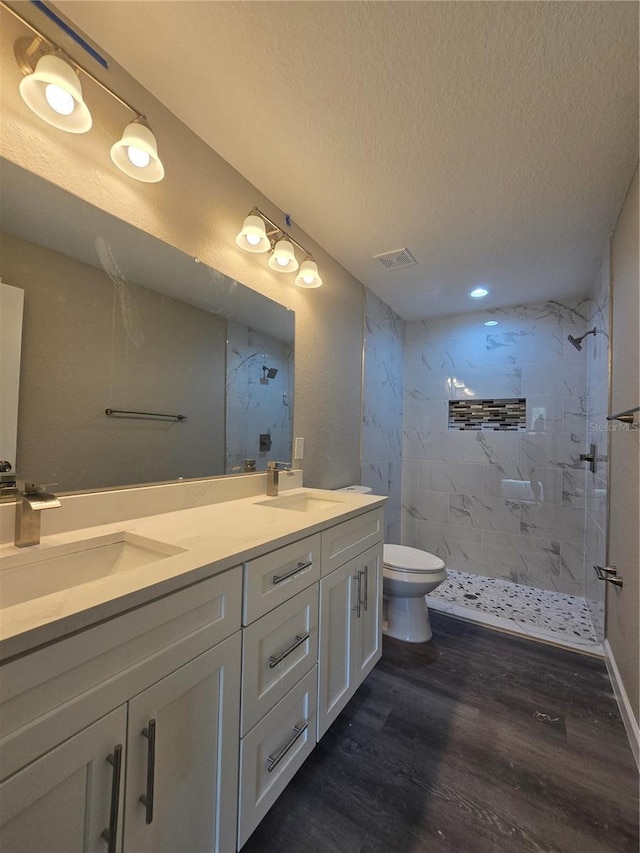 full bath featuring wood finished floors, visible vents, a marble finish shower, and a sink