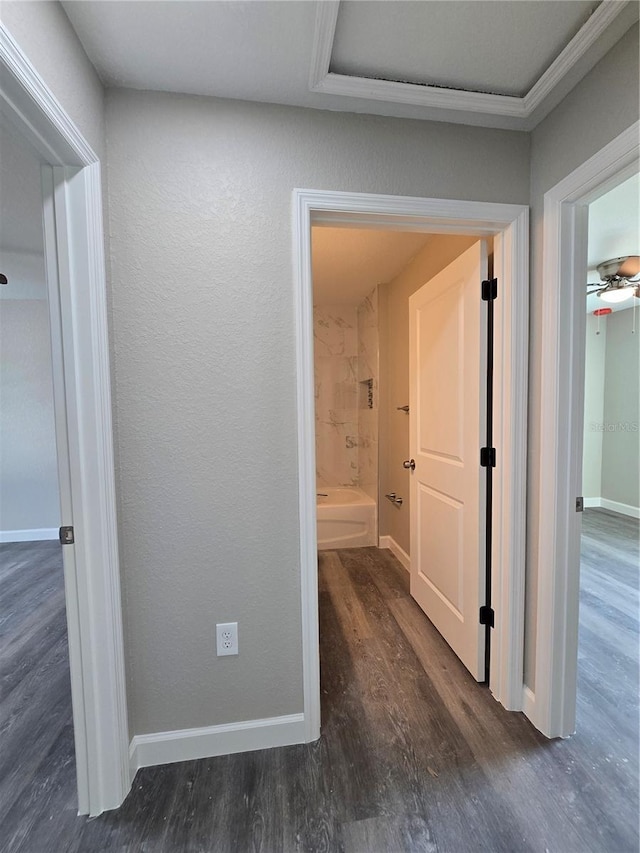 hallway featuring wood finished floors, baseboards, and a textured wall