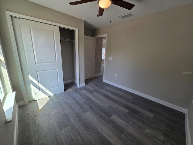 unfurnished bedroom with visible vents, dark wood-style floors, a closet, baseboards, and ceiling fan