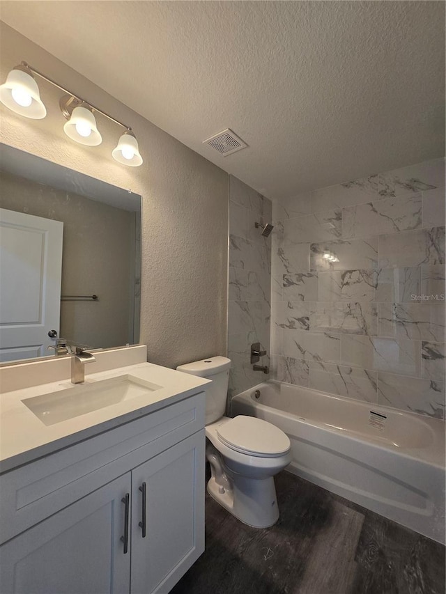 bathroom with visible vents, a textured ceiling, wood finished floors, and a textured wall