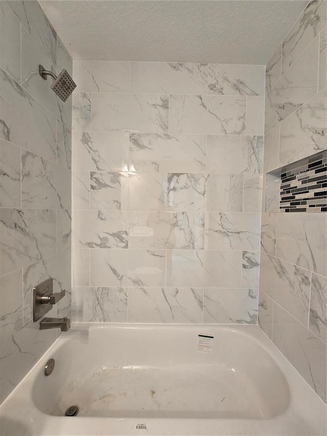 bathroom featuring a textured ceiling and washtub / shower combination