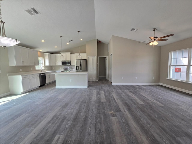 kitchen with visible vents, stainless steel appliances, white cabinets, open floor plan, and a center island