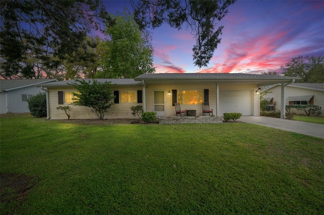 ranch-style home featuring a porch, a yard, a garage, and driveway