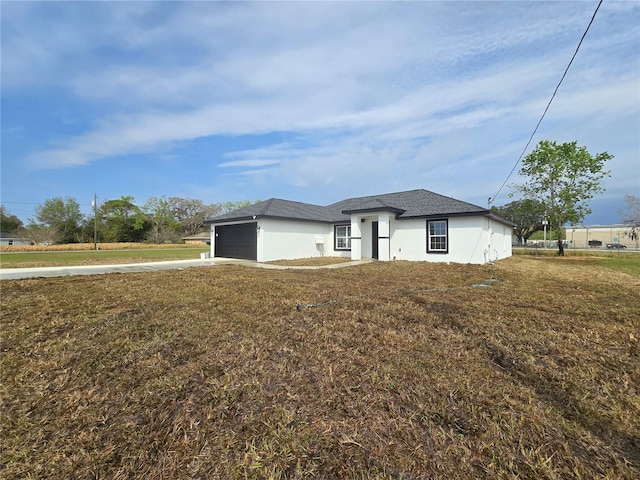 view of front of house with a garage, concrete driveway, a front lawn, and stucco siding