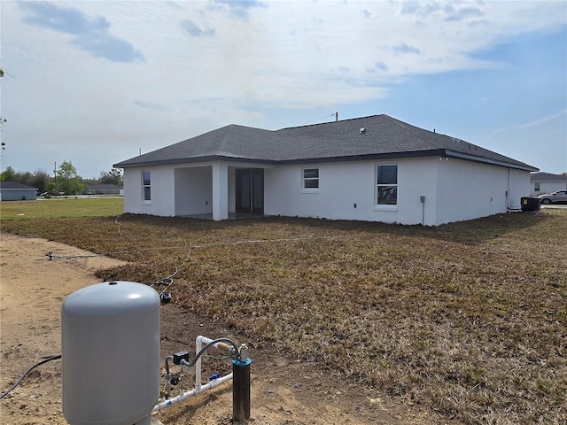 back of house with a lawn and stucco siding