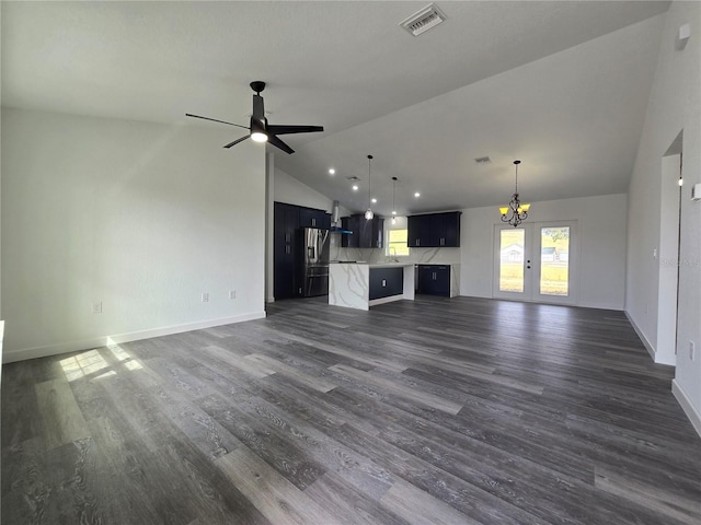 unfurnished living room with visible vents, ceiling fan with notable chandelier, dark wood-type flooring, and baseboards