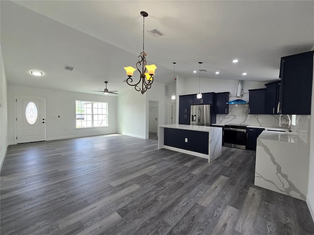 kitchen with visible vents, a kitchen island, wall chimney exhaust hood, stainless steel fridge with ice dispenser, and dark cabinets