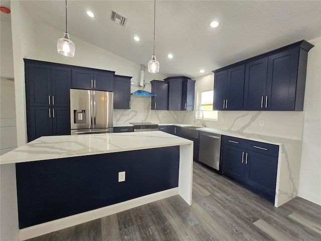 kitchen featuring a kitchen island, wall chimney range hood, light stone counters, stainless steel appliances, and blue cabinets