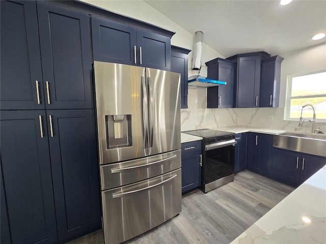 kitchen featuring blue cabinets, a sink, backsplash, stainless steel appliances, and wall chimney exhaust hood