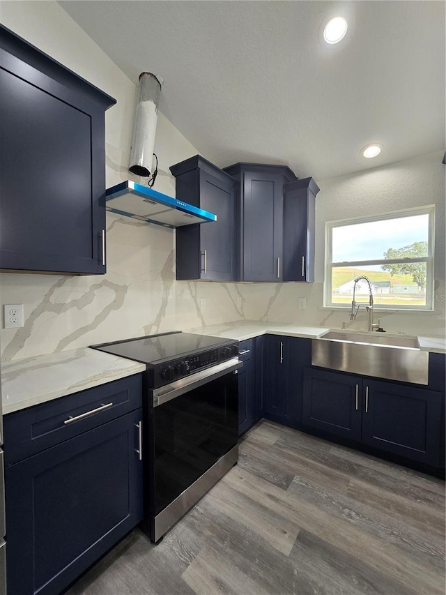 kitchen featuring electric range, a sink, tasteful backsplash, wood finished floors, and wall chimney exhaust hood