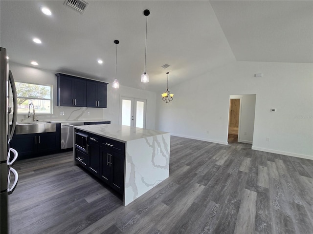 kitchen with visible vents, a kitchen island, vaulted ceiling, appliances with stainless steel finishes, and a sink