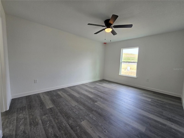 empty room featuring a ceiling fan, dark wood-type flooring, and baseboards