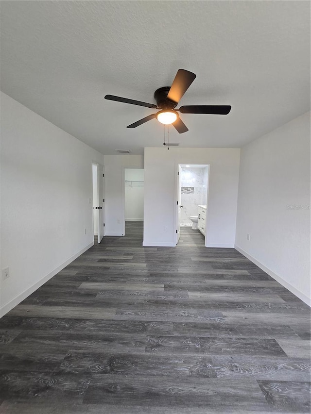 spare room with a textured ceiling, dark wood-type flooring, baseboards, and a ceiling fan