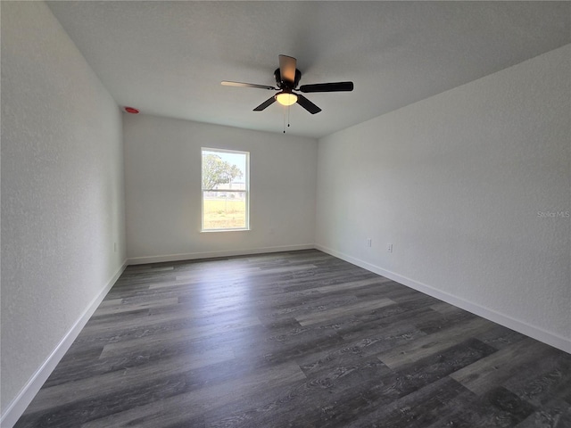 spare room featuring ceiling fan, dark wood-type flooring, baseboards, and a textured wall