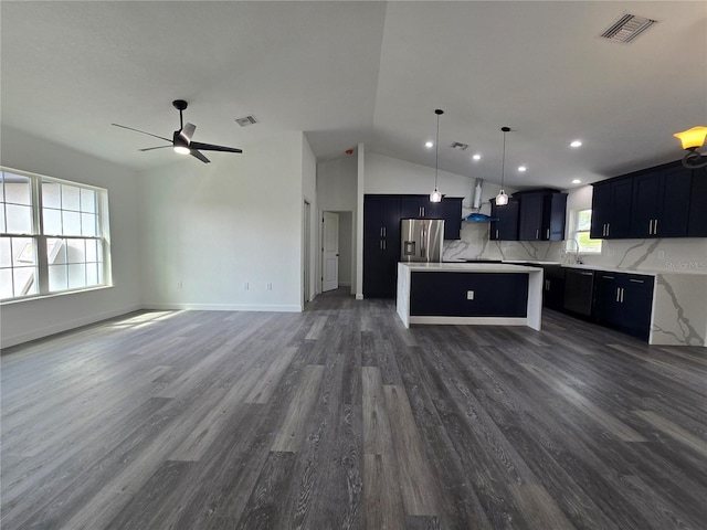 kitchen featuring open floor plan, visible vents, wall chimney range hood, and stainless steel fridge with ice dispenser