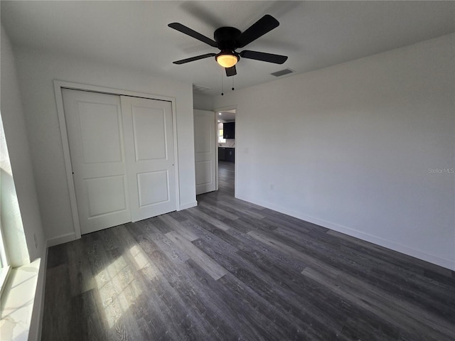 unfurnished bedroom featuring baseboards, visible vents, dark wood finished floors, ceiling fan, and a closet