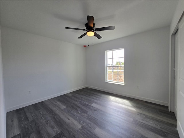 spare room featuring baseboards, dark wood finished floors, and a ceiling fan