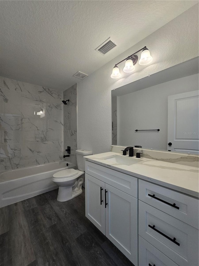 bathroom with visible vents, toilet, a textured ceiling, wood finished floors, and washtub / shower combination