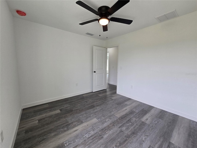 empty room featuring a ceiling fan, baseboards, visible vents, and dark wood-style flooring