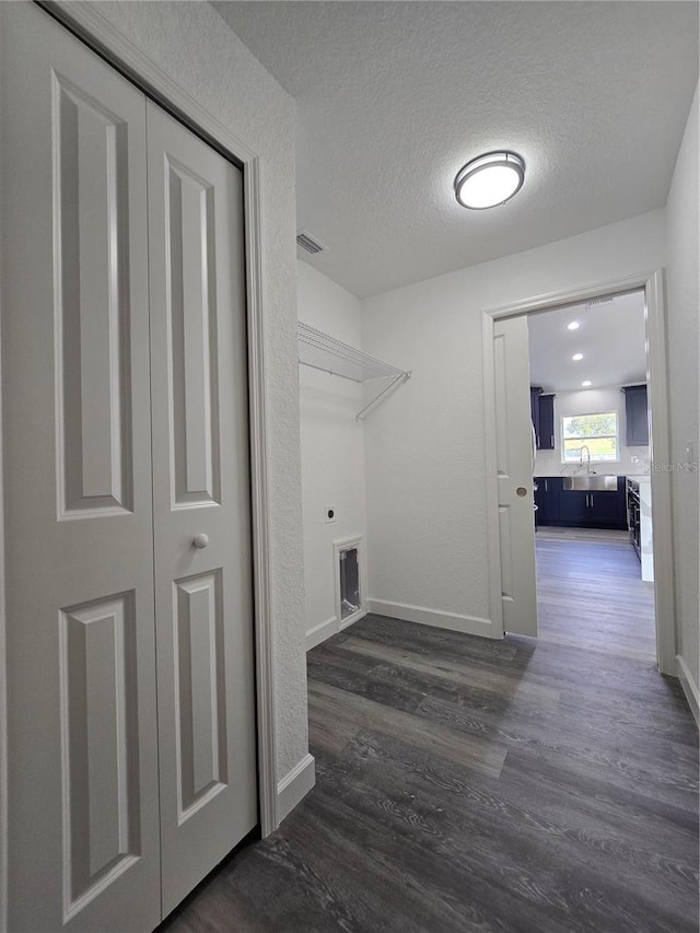 laundry room featuring baseboards, laundry area, hookup for an electric dryer, a textured ceiling, and dark wood-style flooring