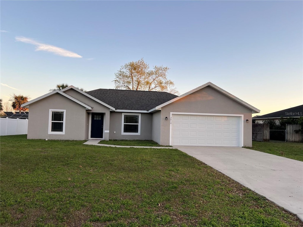 ranch-style home featuring stucco siding, driveway, fence, a front yard, and a garage