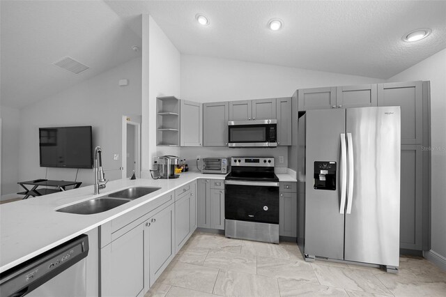 kitchen with gray cabinets, a sink, open shelves, stainless steel appliances, and vaulted ceiling