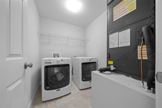 washroom with heating unit, baseboards, laundry area, a textured ceiling, and washer and clothes dryer