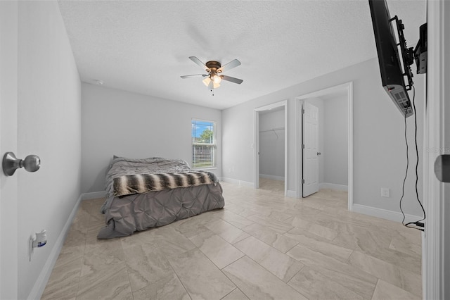 bedroom featuring a spacious closet, baseboards, and a textured ceiling