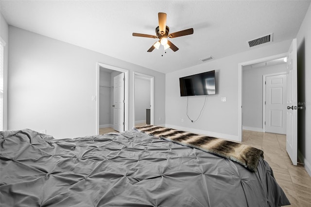 bedroom featuring visible vents, baseboards, a walk in closet, and a ceiling fan