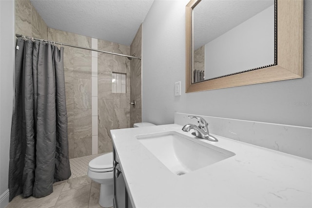 full bath featuring vanity, toilet, a tile shower, and a textured ceiling