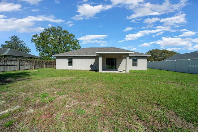 rear view of house featuring stucco siding, a yard, and a fenced backyard