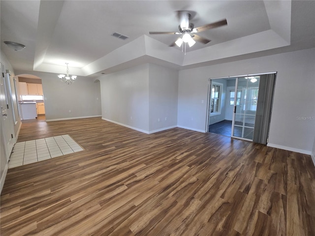 unfurnished room featuring dark wood-style floors, visible vents, baseboards, arched walkways, and a raised ceiling