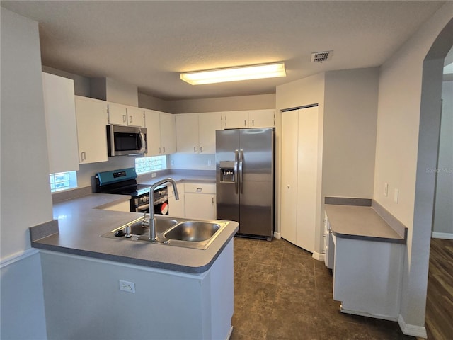 kitchen with visible vents, a peninsula, a sink, appliances with stainless steel finishes, and white cabinetry