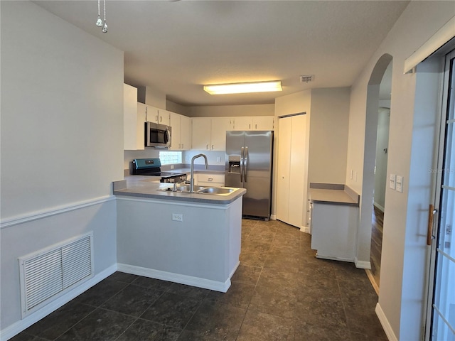 kitchen featuring visible vents, a peninsula, stainless steel appliances, and a sink