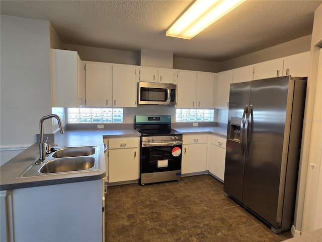 kitchen featuring white cabinetry, a textured ceiling, stainless steel appliances, and a sink