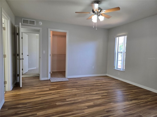 unfurnished bedroom featuring visible vents, dark wood-type flooring, baseboards, a closet, and a ceiling fan