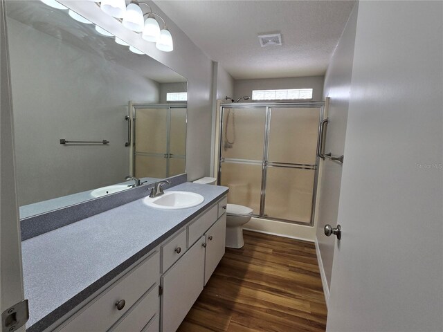 bathroom with vanity, wood finished floors, visible vents, a shower stall, and toilet