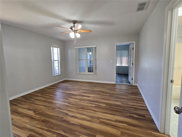 unfurnished room featuring ceiling fan, visible vents, baseboards, and dark wood-style floors