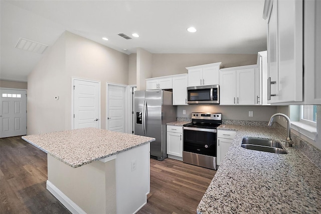 kitchen with visible vents, a sink, stainless steel appliances, vaulted ceiling, and a center island