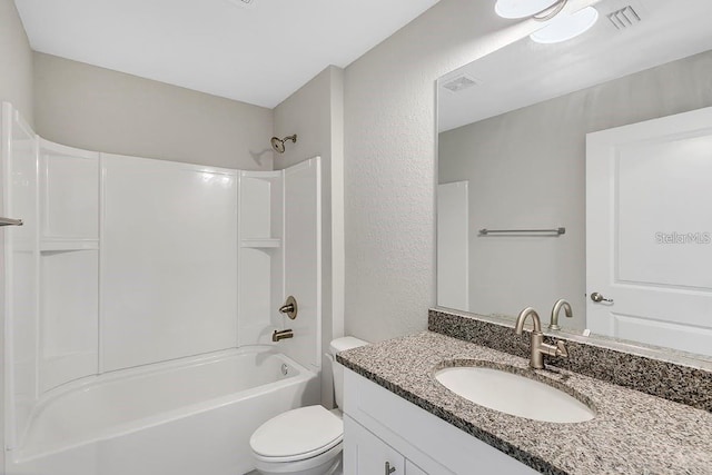 bathroom with visible vents, toilet, vanity, and a textured wall