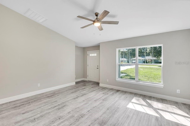 empty room featuring light wood finished floors, visible vents, a ceiling fan, and baseboards