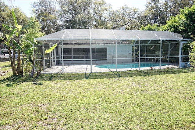 rear view of house with glass enclosure, an outdoor pool, a lawn, and a patio