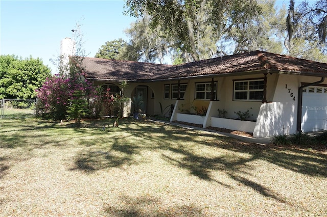 view of front of home with a garage, stucco siding, a front yard, and fence