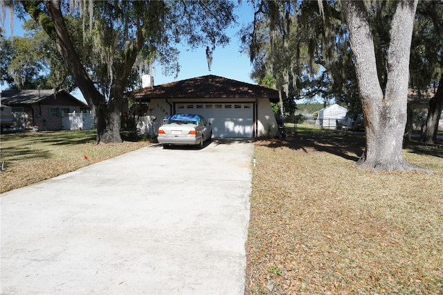 view of front of home with a front lawn, fence, concrete driveway, a garage, and a chimney