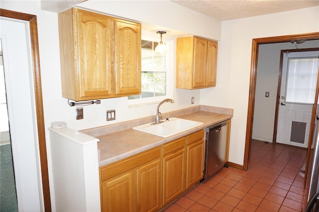 kitchen featuring baseboards, a sink, light countertops, a textured ceiling, and stainless steel dishwasher