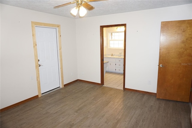 empty room featuring baseboards, a textured ceiling, wood finished floors, and a ceiling fan