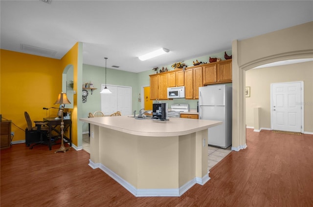 kitchen with arched walkways, white appliances, light countertops, and light wood-style floors