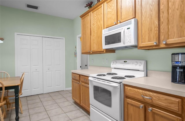 kitchen with light tile patterned floors, visible vents, white appliances, and light countertops