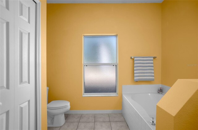 bathroom with tile patterned floors, toilet, a bath, and baseboards